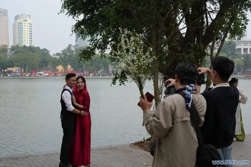 在越南首都河内的还剑湖旁，游客身着越南传统服饰奥黛拍照留念。新华社资料